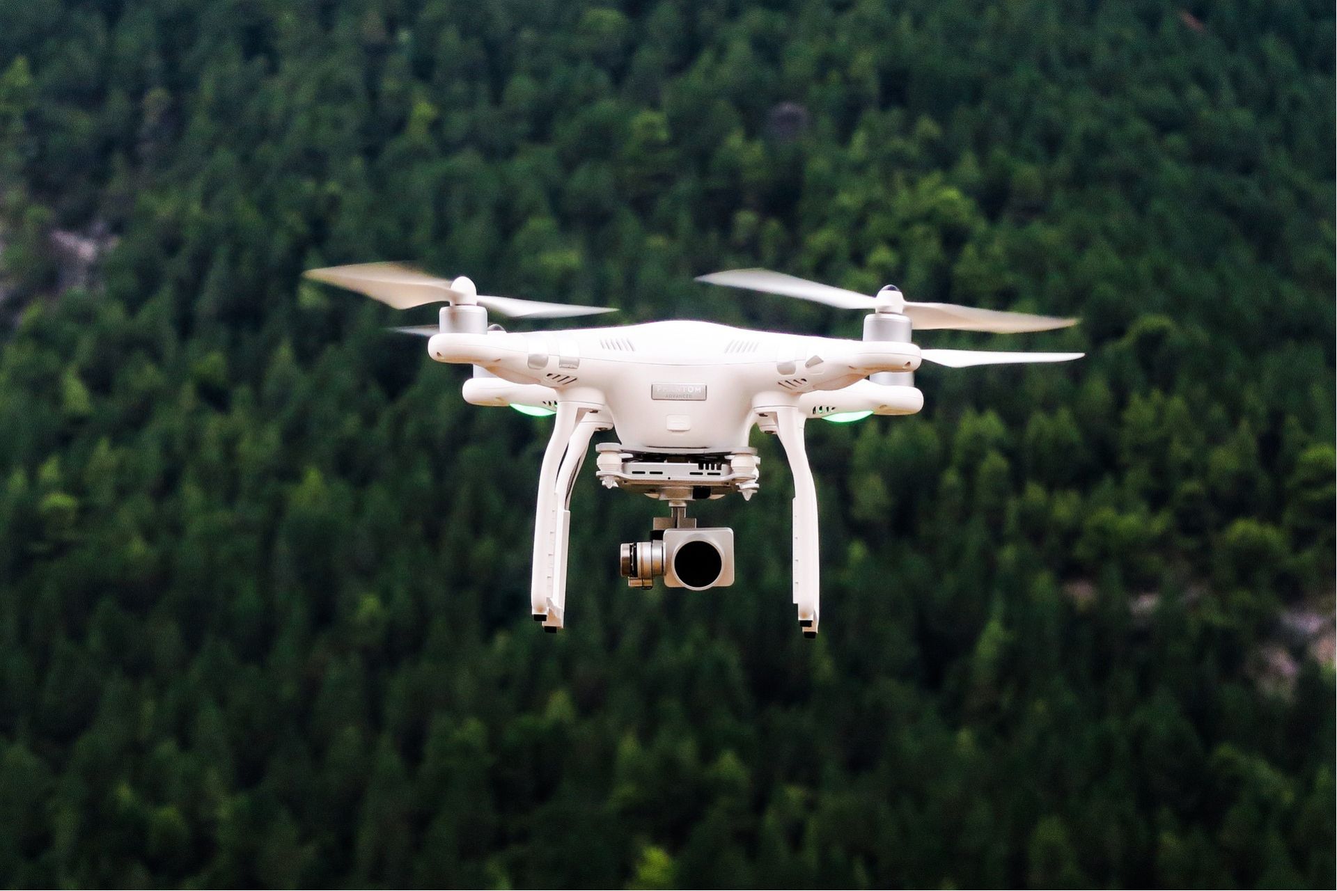 A drone with a camera flying over trees