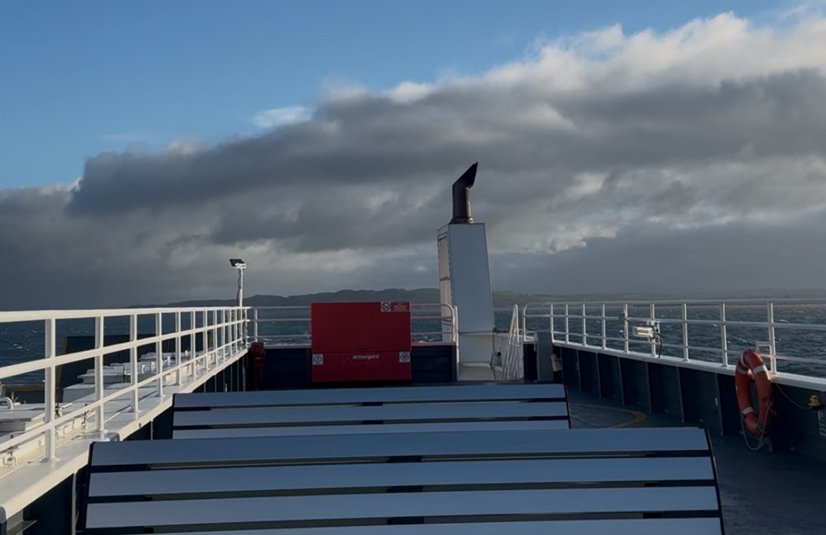 The ferry deck with sea and hills behind