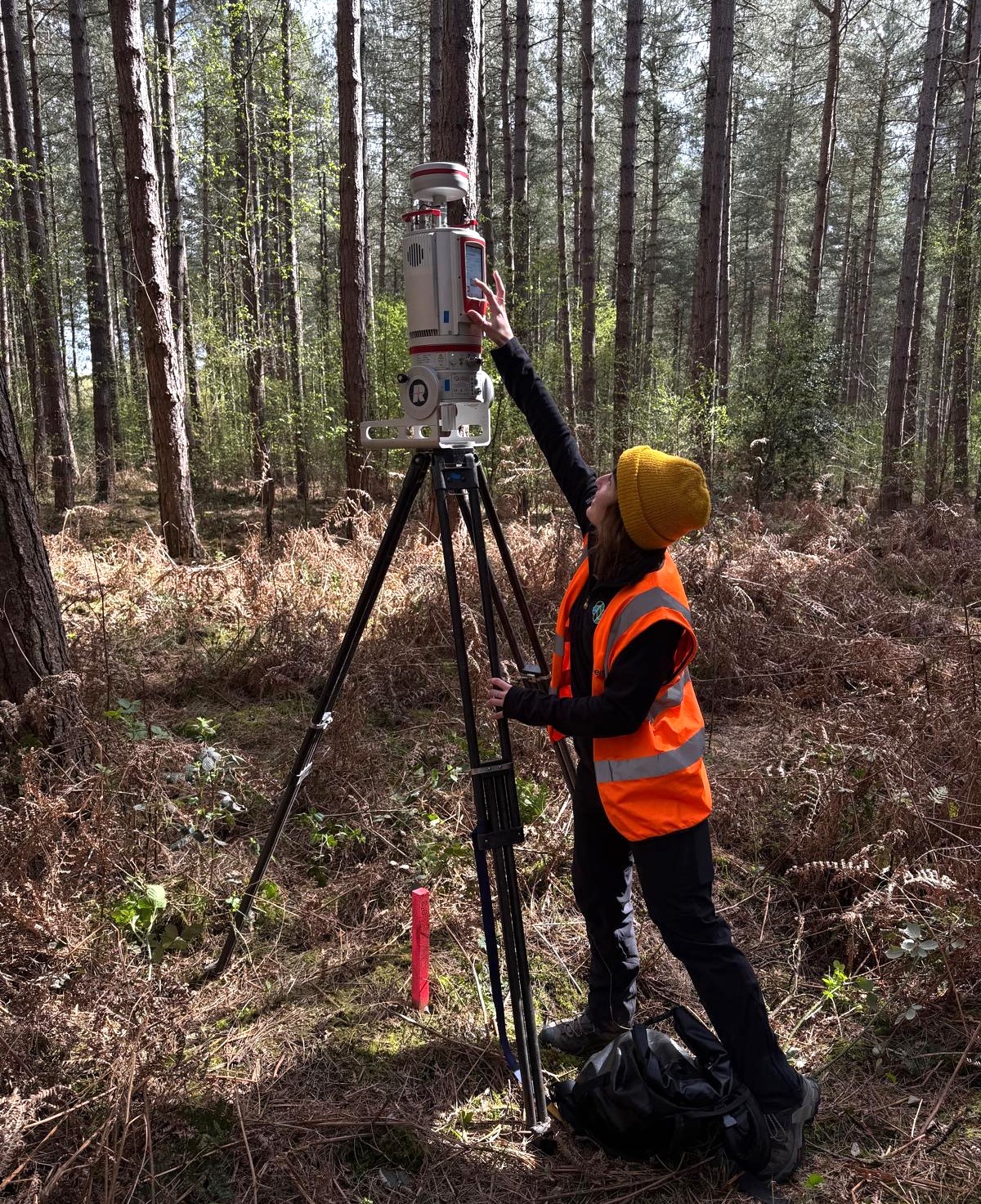 A member of staff using a terrestrial laser scanner in a woodland