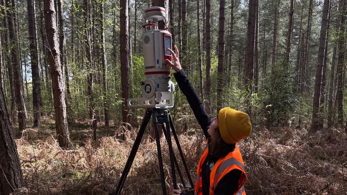 team member checks terrestrial laser scanner in woodland
